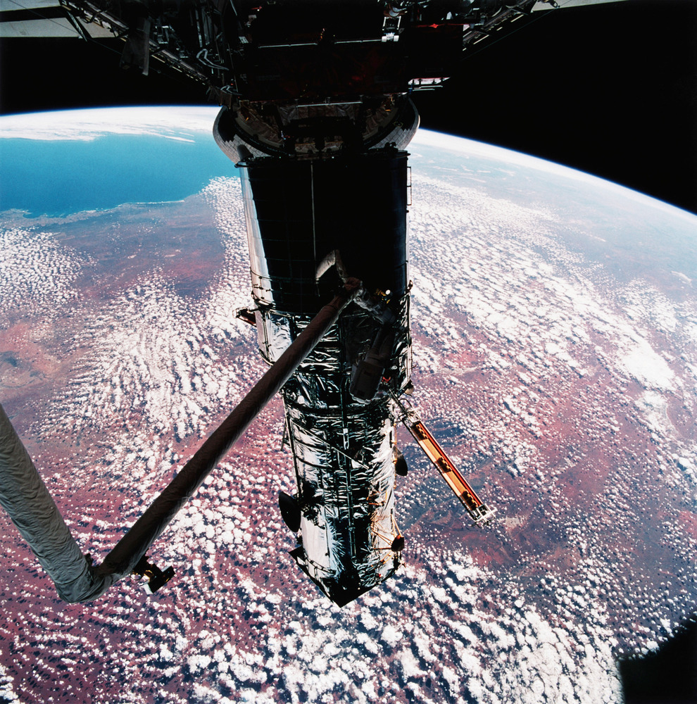 Αστροναύτης κρεμασμένος ανάποδα (πλάκα κάνουμε, δεν υπάρχει "ανάποδα" στο διάστημα) επισκευάζει το τηλεσκόπιο. Στο φόντο, τούτη η Γης που την πατούμε