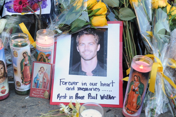 A photo of actor Paul Walker is seen December 1, 2013 among flowers and candles left by fans at the site of the car accident in which the "Fast and Furious" actor and another man died the previous day, in Santa Clarita, California. Santa Clarita police warned fans Monday against "burning rubber" near the spot where the car Walker was a passenger in crashed, as they continued to probe the accident. Police issued the caution after reports of people pulling stunt maneuvers on the stretch of road in town northwest of Los Angeles, where Walker died on Saturday. AFP PHOTO / Robyn Beck (Photo credit should read ROBYN BECK/AFP/Getty Images)
