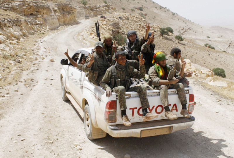 FILE PHOTO AP PROVIDES ACCESS TO THIS HANDOUT PHOTO TO BE USED SOLELY TO ILLUSTRATE NEWS REPORTING OR COMMENTARY ON THE FACTS OR EVENTS DEPICTED IN THIS IMAGE. THIS IMAGE MAY ONLY BE USED FOR 14 DAYS FROM TIME OF TRANSMISSION; NO ARCHIVING; NO LICENSING. FILE - In this file photo released on May 20, 2015, provided by the Kurdish fighters of the People's Protection Units (YPG), which has been authenticated based on its contents and other AP reporting, Kurdish fighters of the YPG, flash victory signs as they sit on their pickup on their way to battle against the Islamic State, near Kezwan mountain, northeast Syria. Drawing on thousands of fighters from Syria's mix of religious and ethnic groups, a U.S.-backed alliance called the Syrian Democratic Forces has emerged as the most effective fighting force against the Islamic State group in Syria.(The Kurdish fighters of the People's Protection Units via AP, File)