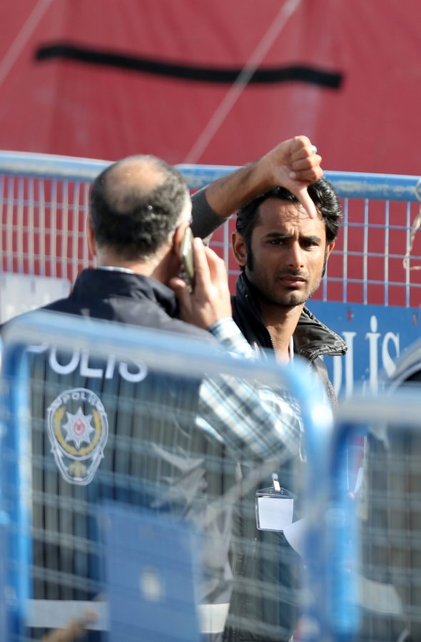 epa05243100 A man flashes a 'Thumb-down' gesture as he is escorted by Turkish police upon the arrival of migrants by ferry from the Greek island of Lesvos (Lesbos) at the Dikili harbour in Izmir, Turkey, 04 April 2016. Some 160 migrants, from Pakistan, Bangladesh and Morroco, who refused to apply for asylum, have been deported on 04 April early morning to Turkey, after an agreement between the European Union (EU) and Turkey on the refugees crisis. EPA/TOLGA BOZOGLU